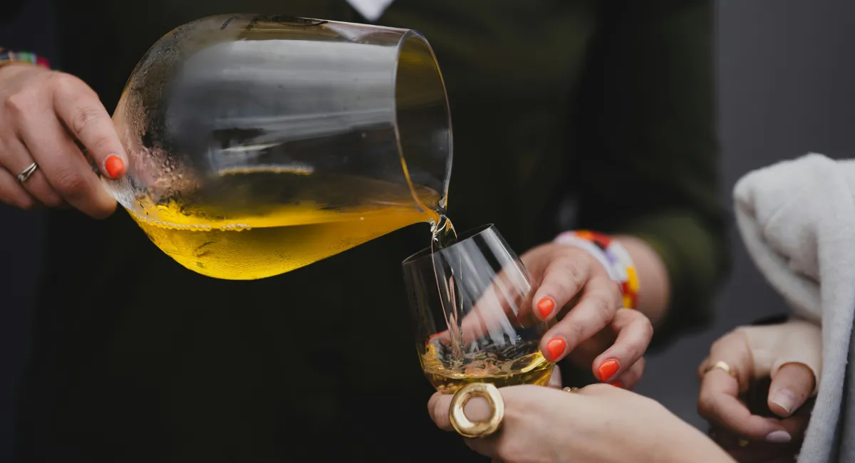 Vin blanc servi en carafe avec mains